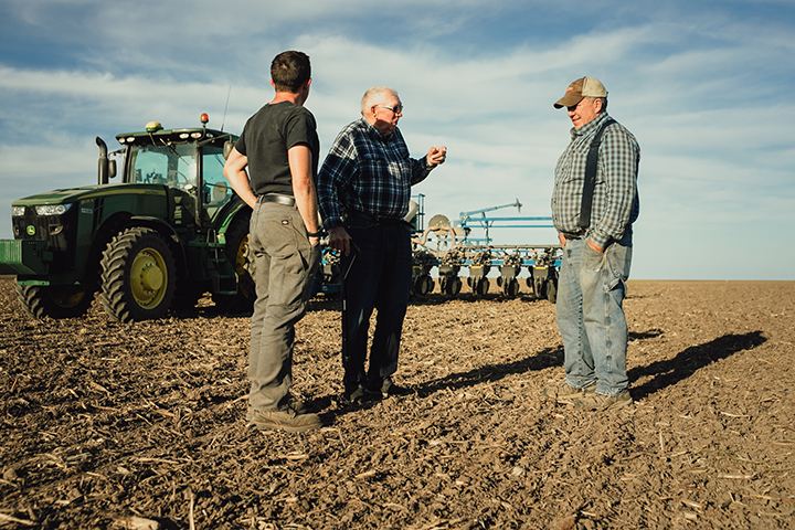 Farmers in a field with a tractor having a discussion